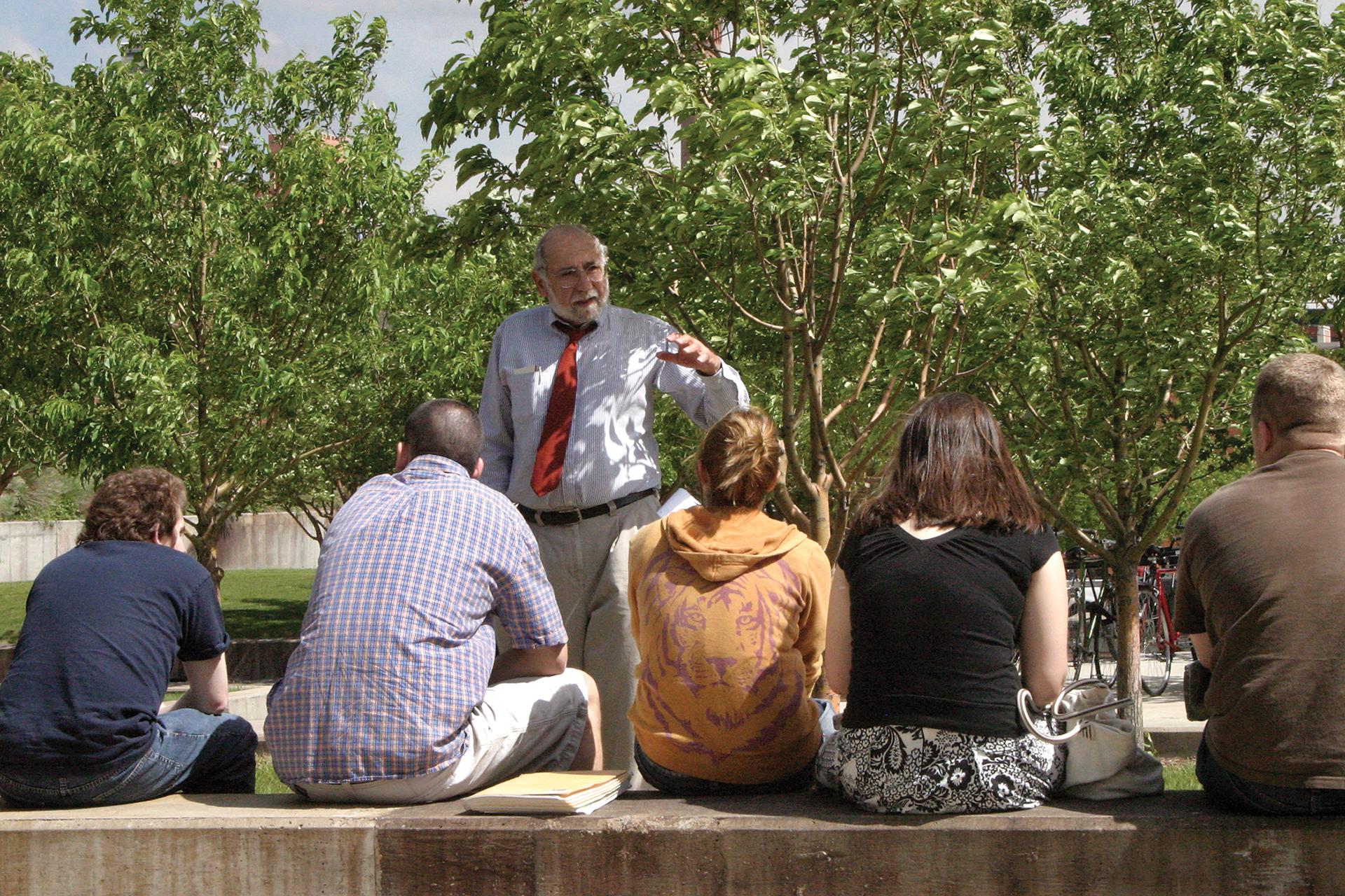 Older man teaching a small class in an outside setting