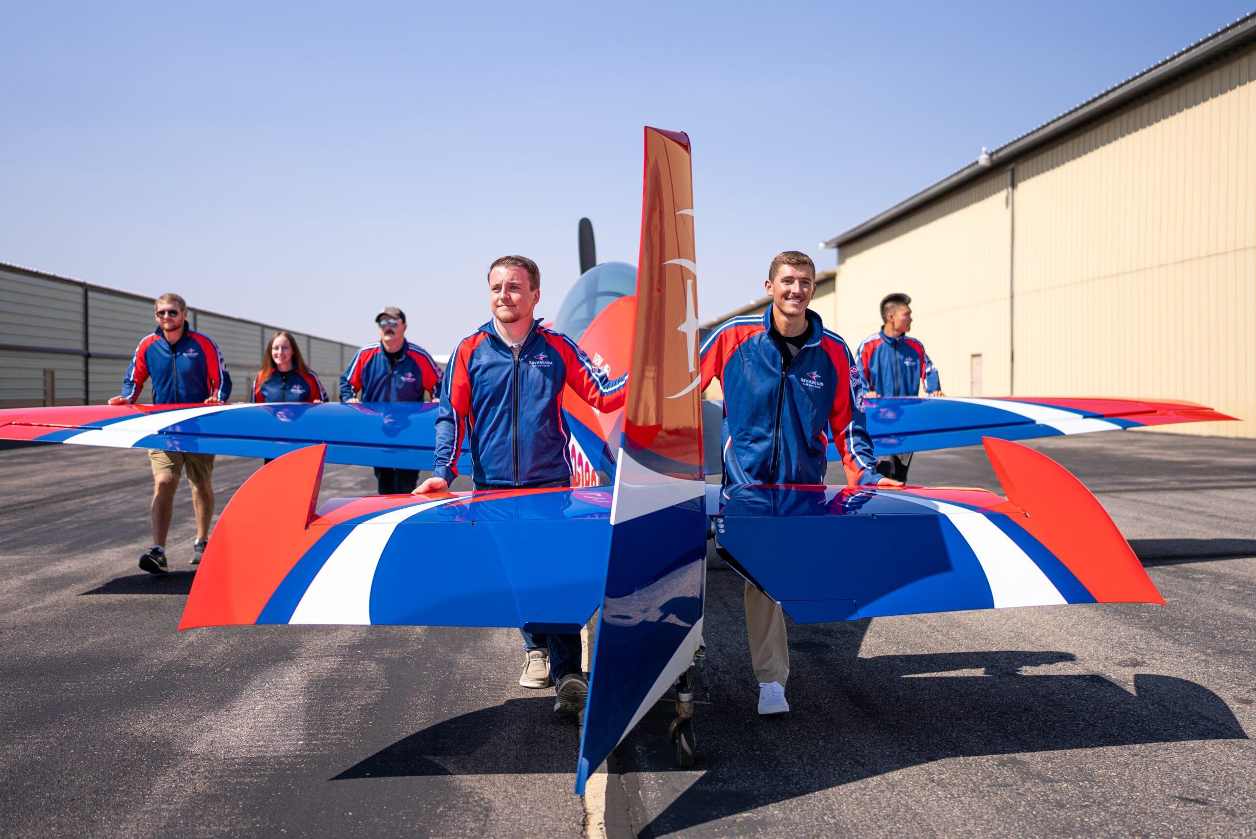 MSU Denver Aerobatics student, Brayden Berringer and Braeden Giltinan, and others pull the GB1 Gamebird to the runway.